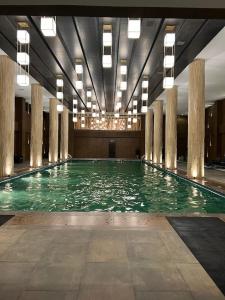 a large swimming pool in a building with columns at Designer 1 bedroom , self check-in , pool & sauna in Rawalpindi