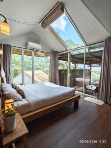 a bedroom with a large bed with a large window at U Garden in Ban Huai Khai