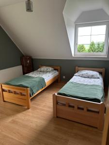 two twin beds in a room with a window at Willa nad stawem in Mezowo
