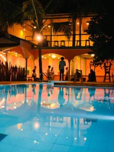 a group of people standing around a swimming pool at night at Laughing Leopard Trinco in Trincomalee