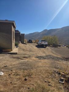 a white truck parked in a yard with mountains in the background at Lillies House in Mokoeng