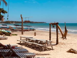 a beach with wooden tables and chairs and the ocean at Laughing Leopard Trinco in Trincomalee
