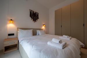 a bedroom with a white bed with towels on it at Asini deluxe suite 4, with rooftop terrace and breathtaking views in Asíni