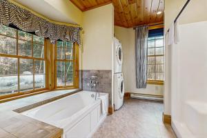 a bathroom with a tub and a washer and dryer at Garfield's Grand View in Bethlehem +39 photos