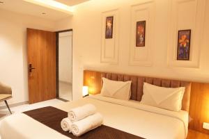 a bedroom with a large white bed with two rolled towels at Hotel Madhuram Shivpuri MP in Shivpurī +16 photos