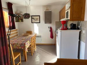 a kitchen with a table and a white refrigerator at Appartement avec balcon 6 personnes Superdévoluy in Le Dévoluy +30 photos