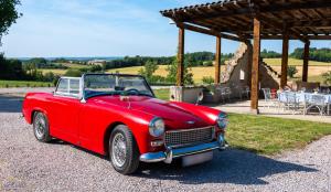 a red car parked in front of a pavilion at Luxury Gites de Chateau Mirabel - Latour - with saltwater swimming pool and AC in Puylaurens