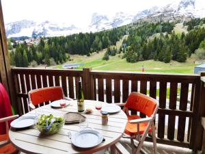 a table with a bowl of grapes and a bottle of wine on a balcony at Appartement avec balcon 6 personnes Superdévoluy in Le Dévoluy