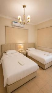 a bedroom with two beds and a chandelier at شالية البردايس درة العروس من ارقى الشاليهات in Durat Alarous