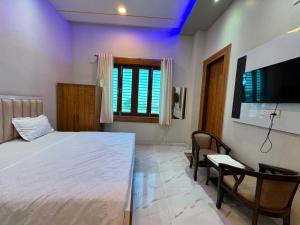 a bedroom with a bed and a flat screen tv at Atmosphere Hotel & Restaurant in Alīgarh