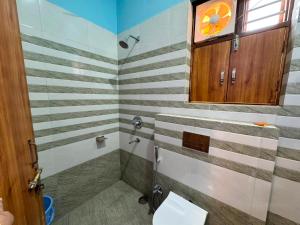 a bathroom with striped walls and a toilet and a window at Atmosphere Hotel & Restaurant in Alīgarh