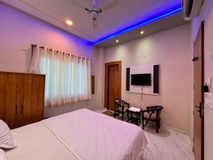 a bedroom with a bed and a table and a tv at Atmosphere Hotel & Restaurant in Alīgarh