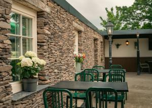 a patio with tables and chairs and a stone wall at Adams Townhouse in Dingle