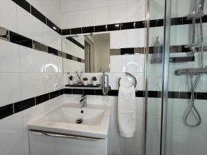 a white bathroom with a sink and a shower at Studio moderne climatisé - Parking gratuit - Paris & Disney in Ormesson-sur-Marne