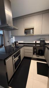 a kitchen with white cabinets and a black counter top at Apartamento 2 quartos com ar-condicionado, Wi-Fi e Netflix in Americana +3 photos