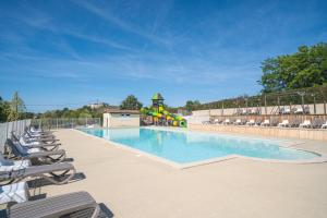a swimming pool with lounge chairs and a playground at Ludocamping in Lussas