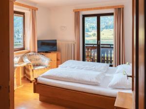 a bedroom with a bed and a chair and a window at Hotel Lipeter & Bergheimat in Weissensee