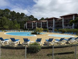 a group of chairs and a pool in a resort at Superbe appartement 6 personnes in Biscarrosse