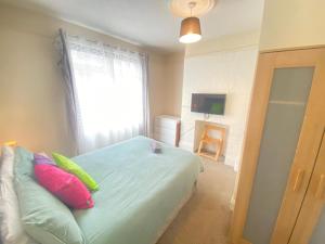 a bedroom with a bed with colorful pillows and a window at 4-5 Bedroom House For Corporate Stays in Kettering in Kettering