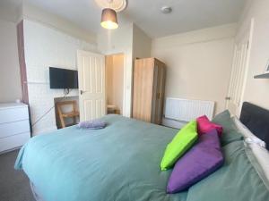 a bedroom with a bed with purple and green pillows at 4-5 Bedroom House For Corporate Stays in Kettering in Kettering +11 photos