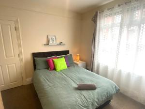 a bedroom with a bed with colorful pillows and a window at 4-5 Bedroom House For Corporate Stays in Kettering in Kettering