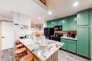 a kitchen with green cabinets and a marble counter top at Crestview 48 in Mammoth Lakes