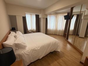 a bedroom with a white bed and a mirror at Hotel CHG LEYTON in Foz