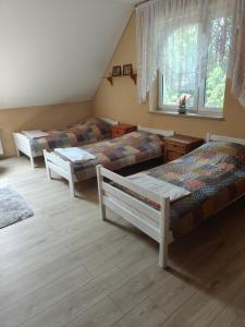 a living room with three beds and a window at Lipowy Dworek Pensjonat in Staroguby