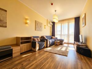 a living room with a couch and a tv at Europroperties Golden Line in Golden Sands