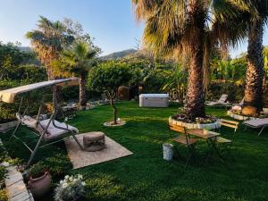 a garden with palm trees and a swing at Villa Tiche in Cefalù