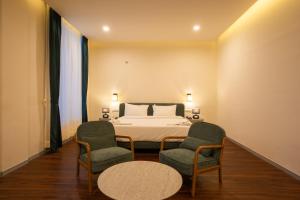 a bedroom with a bed and two chairs and a table at Aanya Taara Resort- Mettupalayam in Mettuppālaiyam