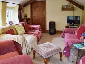 a living room with pink couches and a tv at The Old Barn in Abbotsham