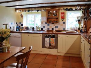a kitchen with white cabinets and a sink and a table at The Old Barn in Abbotsham +13 photos