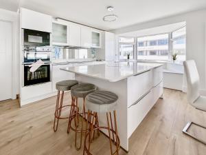 a kitchen with white cabinets and a large island with stools at The Beach House in Worthing
