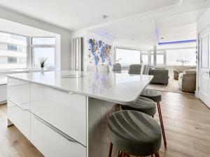 a white kitchen with a counter and stools at The Beach House in Worthing +22 photos