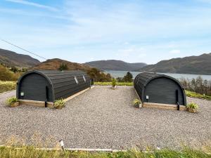 two storage sheds sitting on top of gravel next to a lake at Duich - Uk50716 in Kirkton