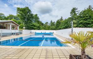 a large swimming pool with a white fence and trees at One-Bedroom Apartment In Ebeltoft in Ebeltoft