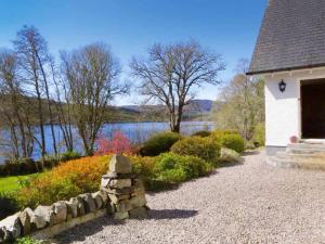 a stone wall next to a building with a lake at Lochview Guesthouse in Contin
