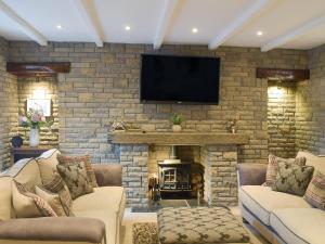 a living room with a stone fireplace with a flat screen tv at Tennox Farm House - Uk36254 in Kilbirnie