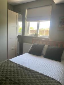 a bedroom with a bed with white sheets and a window at High Tide in Whitstable