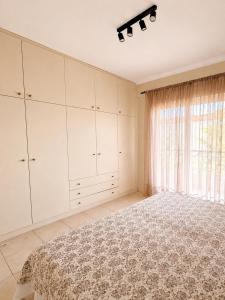 a white bedroom with a bed and a window at Agapidis Apartment in Hanioti