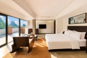 a bedroom with a large white bed and a large window at The Dragons Rest Sanctuary-Yulong River Branch - Infinity Pool & Cafe - English Speaking Service - Free MTB Rental & Tailor-Made Tour Service in Yangshuo