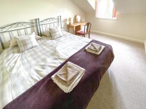 a bedroom with a large bed with two towels on it at Lily Pad 2 - Uk43901 in Nassington +16 photos