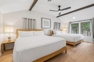 a white bedroom with two beds and a window at 3BR Cabin Sleeps 10 Fenced Yard in Oklahoma City