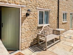 a wooden bench sitting outside of a building with a door at Lily Pad 5 - Uk43913 in Nassington +19 photos