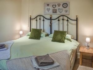 a bedroom with a large bed with green sheets and pillows at Lily Pad 1 - Uk49648 in Nassington