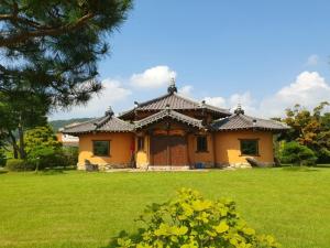 a yellow house with a roof on a green field at Boseong Carmel Royal Pension in Boseong