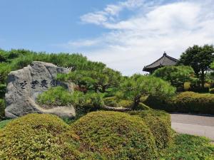 a garden with a tree and a rock and a building at Boseong Carmel Royal Pension in Boseong