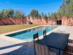 a table and chairs next to a swimming pool at Villa Marrakech Rouge in Aït Zat