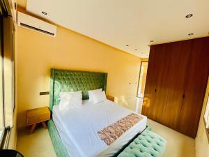 a bedroom with a large bed with a green headboard at Villa Marrakech Rouge in Aït Zat +17 photos
